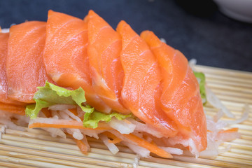 Close up raw fresh salmon sashimi set salad  on black table.