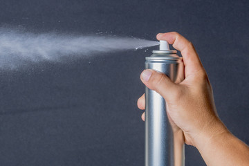 The hand is holding spray bottle with a black background.