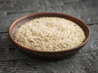 Clay bowl on the black table, filled with salt with herbs.