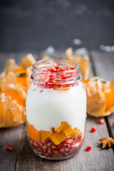 Healthy breakfast with yogurt, persimmon and pomergranate seeds. Selective focus. Shallow depth of field.