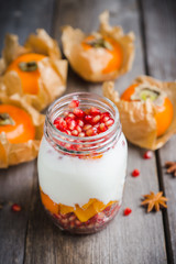 Healthy breakfast with yogurt, persimmon and pomergranate seeds. Selective focus. Shallow depth of field.