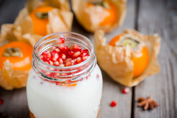 Healthy breakfast with yogurt, persimmon and pomergranate seeds. Selective focus. Shallow depth of field.