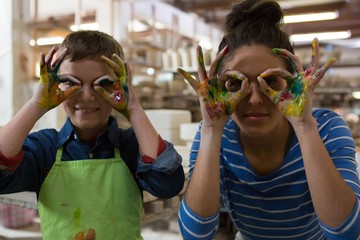 Mother and son gesturing in pottery workshop