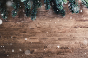 Green Christmas tree pine leaves and snow on wood table background
