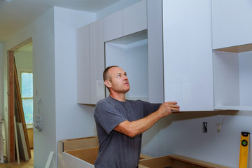 Closeup of a cabinet installer installing hardware on new kitchen cabinets.
