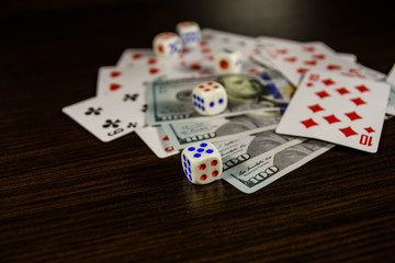 Playing cards, dice and one hundred dollar bills on a dark wooden table