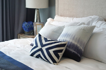 Comfortable blue pattern cushions and white pillows on the white bed