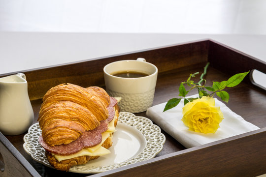 fresh croissant with cheese and sausages cup of black coffee breakfast idea.