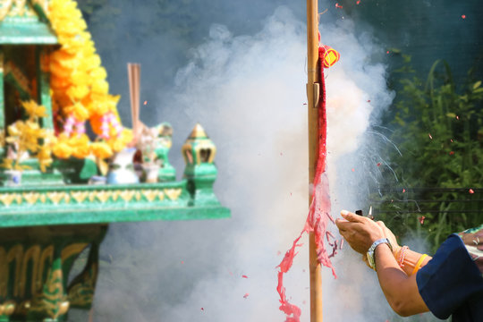 Asian people with firecrackers pay respect to shrine or spirit worship