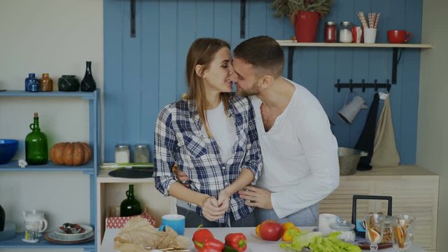 Attractive loving couple having fun in the kitchen. Handsome man juggle with fruits to impress his girlfriend