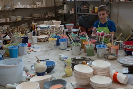Boy Painting A Bowl In Pottery Shop