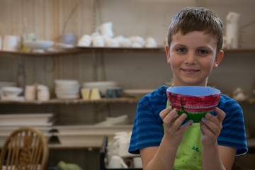 Boy holding a panted pot in pottery workshop