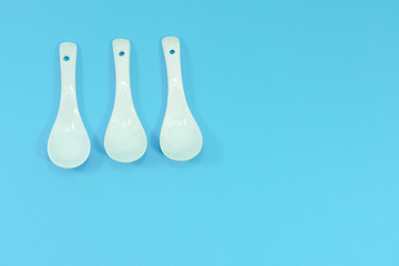 Ceramic white spoon on blue background