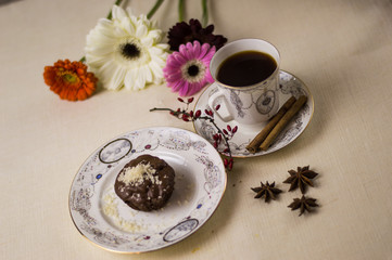 Chocolate fondant on a white plate with coffee and flowers