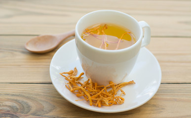 .Dried Cordyceps Militaris Mushroom with Cup on wooden table background