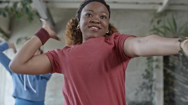 Medium Shot Of Smiling Black Woman With Curly Hair Doing Aerobics In Group Class