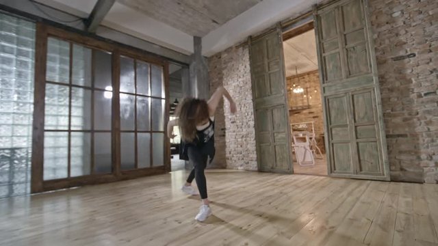 PAN of cheerful female dancer improvising in empty loft