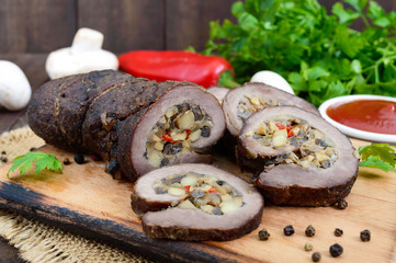 Meatloaf (roll) stuffed with mushrooms, sweet pepper and tomato sauce on a dark wooden background. Festive dish