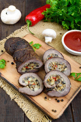Meatloaf (roll) stuffed with mushrooms, sweet pepper and tomato sauce on a dark wooden background. Festive dish