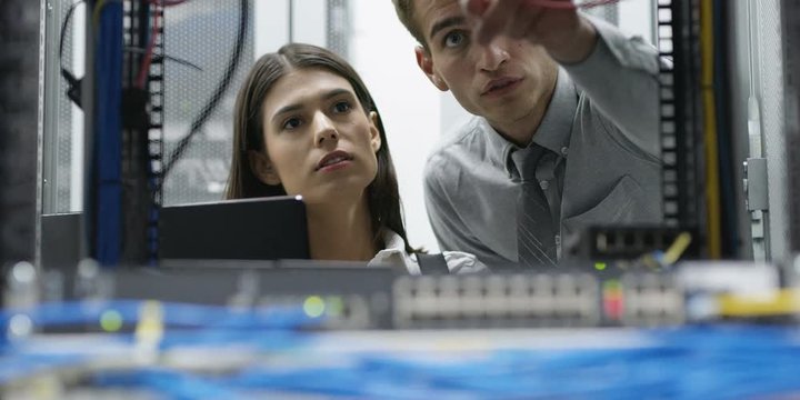 Team of people working in a data centre with rows of server racks and super computers. Shot on RED Helium 8K