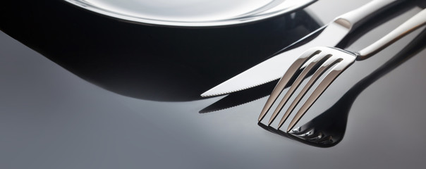 Empty plate with knife and fork on a black background