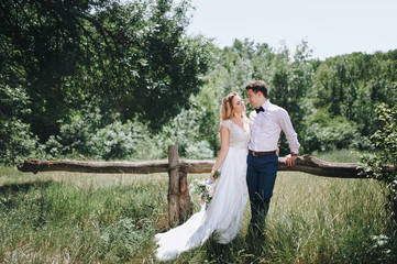 The groom in the white shirt and bride are smiling and looking at each other. The bride is holding...