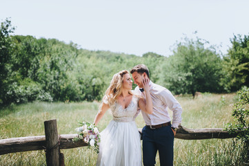 The newlyweds are smiling cheerfully. A wedding walk in the summer forest.