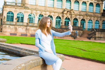 Girl makes photos shots of european city Dresden and selfie of background old German town