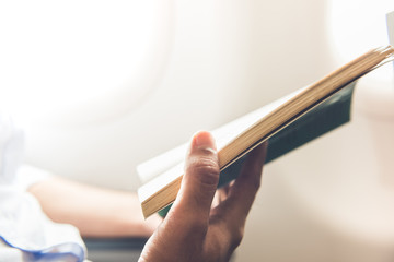 Passenger killing time by reading book while traveling on the plane