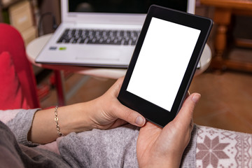 Woman hands holding ebook and reading on couch. Blank screen.