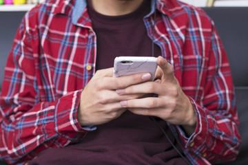 Fototapeta premium young adult or teenager with mobile phone and headphones at home