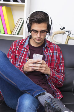 young adult or teenager with mobile phone and headphones at home