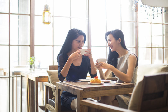 Best female friends drinking coffee in cafe_