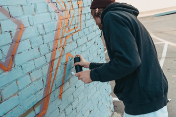 street artist painting colorful graffiti on wall of building