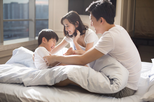Cheerful young family having fun on a bed