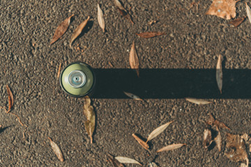 top view of can with spray paint on asphalt with shadow