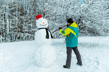 man making snowman in winter day