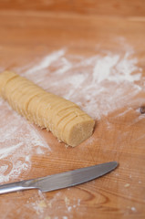 Roll of sugar butter cookie dough on flour dusted wooden surface to make  traditional German Christmas butter cookies called Engelsaugen or Husarenkrapfen