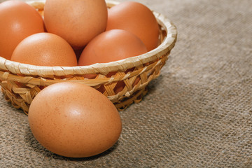 Easter composition. Some eggs in a straw basket on a fabric background closeup