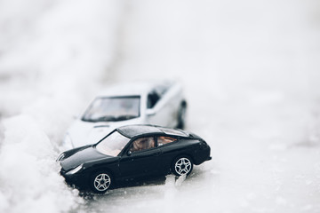 Symbolic car accident in winter on snow road staged with toy cars