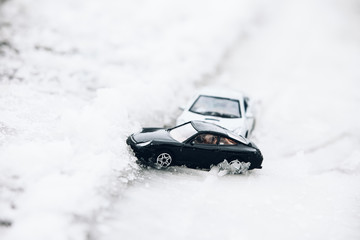 Symbolic car accident in winter on snow road staged with toy cars