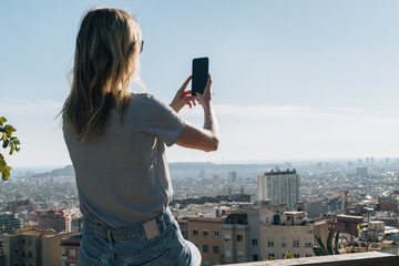 Rear view of young woman wearing in stripped t-shirt and jeans sitting on high point and...