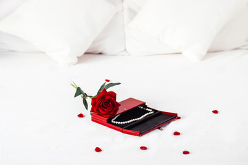 Valentines day surprise at morning on the white bed for her. Red heart background with rose with box. copy space