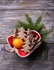 Oatmeal gingerbread cookies in the shape of Christmas tree sprinkled with powdered sugar with tangerines in a basket on a wooden table, rustic style, selective focus