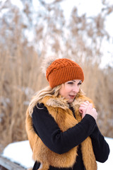 beautiful girl in a fur vest walks in a field in the snow