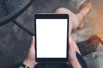 Top view mockup image of a woman sitting crossed legs holding black tablet pc with blank white screen