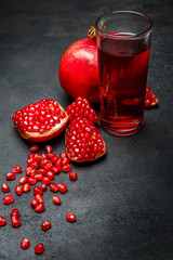 Pomegranate juice and seeds close-up on dark concrete background