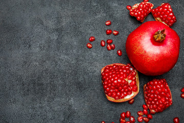 Pomegranate and seeds close-up on dark concrete background