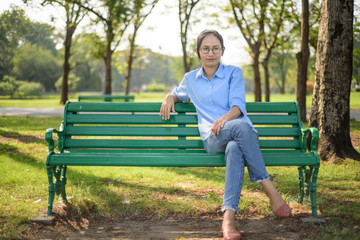 Asian woman sitting on bench in the gargen.