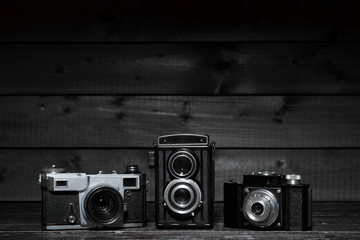 Three film cameras on a dark wooden background